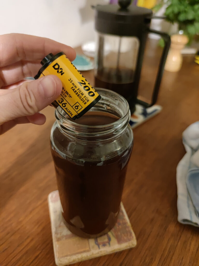 Eine Hand hält einen der Filme über ein mit heißem Kaffee gefülltes Schraubglas. 